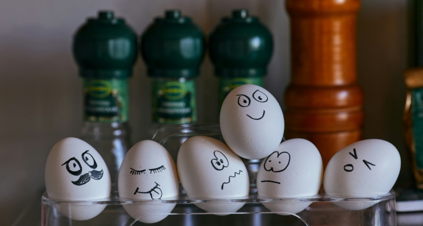 Painted faces on eggs on a glass rack